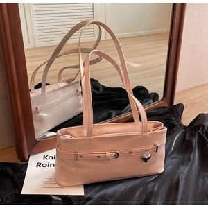 Detail of pink patent leather shoulder bag with metallic heart charm and belt buckle