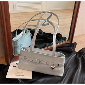Close-up of light blue glossy shoulder bag with silver heart charm and belt buckle detail