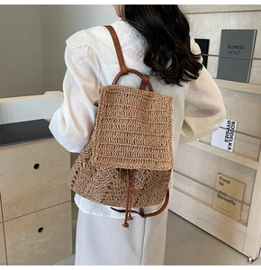 Detailed close-up of the intricate woven pattern and brown leather straps on a straw backpack