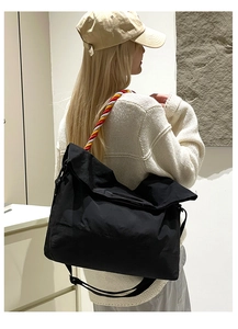 Détail du sac cabas en toile noire avec une poignée en corde tressée à trois couleurs