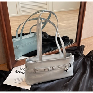 Detail of light gray patent leather shoulder bag with silver heart charm and metal eyelets