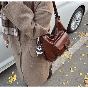 Brown vintage faux leather crossbody bag detail with a cute knitted puppy charm attached