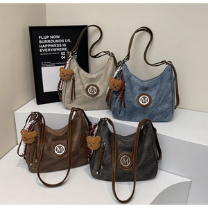 Dettaglio di quattro borse hobo vintage in vari colori con ciondoli a forma di orso