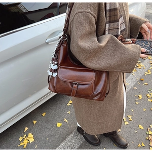 Detail of dark brown leather tote featuring a retro buckle pocket and cute puppy charm