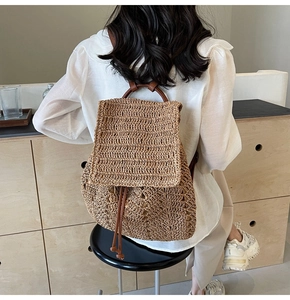 Detail of hand-woven straw backpack featuring brown leather straps and drawstring closure
