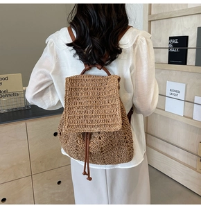 Detail of woven straw backpack showing natural texture, drawstring and leather handle