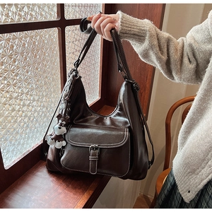 Macro shot of dark brown oil wax PU leather bag with large pocket and puppy charm detail