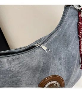 Dettaglio della cerniera in metallo argento su borsa tote in denim azzurro chiaro