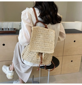 Detail of hand-woven texture and brown PU leather straps on a summer straw backpack