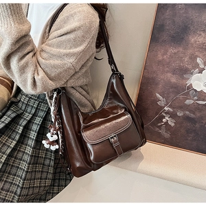 Detail of dark coffee hobo bag in glossy leather with a cute dog charm and front pocket