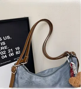 Dettaglio della borsa tote in denim blu con manici in pelle marrone e cuciture bianche