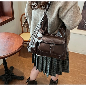 Detail of dark brown vintage faux leather shoulder bag with buckle pocket and dog pendant