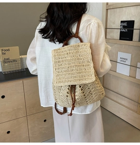 Close-up of woven straw backpack with brown leather straps on a white linen shirt