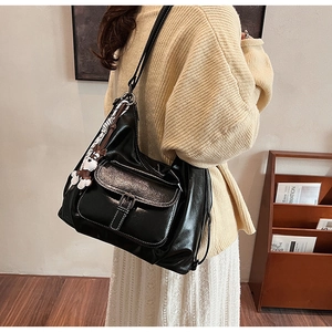 Detail of black glossy tote bag with white contrast stitching and cute dog charm pendant