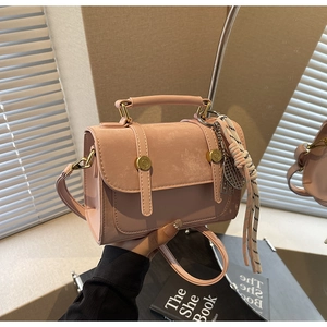 Dettaglio di una borsa a tracolla rosa pastello con fibbie dorate e manico