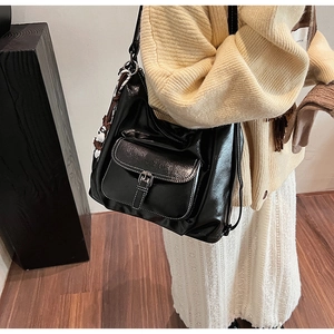 Detail of black PU leather shoulder bag featuring white contrast stitching and buckle pocket