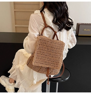 Detail of handwoven straw backpack with brown leather straps on a white summer dress
