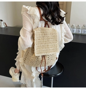 Detail of straw backpack showing woven texture with brown leather straps and drawstring