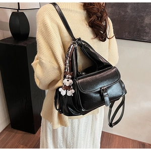 Close-up of shiny black vintage backpack with decorative silk scarf and cute dog pendant