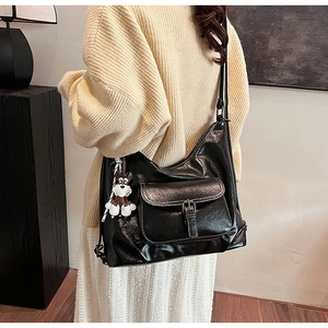 Detail view of glossy black leather tote bag with a cute cartoon dog charm accessory