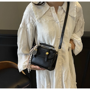 Dettaglio della mini borsa quadrata in pelle nera con chiusura d'oro e nappa