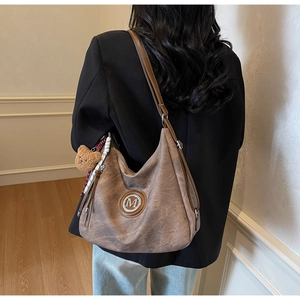 Dettaglio della borsa hobo in pelle marrone con logo M dorato e sciarpa di seta decorativa