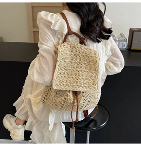 Detail of hand-woven straw backpack with leather trim worn with a summer dress