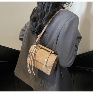 Dettaglio della borsa a tracolla in pelle PU kaki con cinghie decorative sul modello