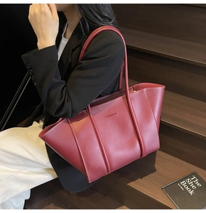 Detail of burgundy leather tote bag with FASHION embossment shown in a lifestyle setting