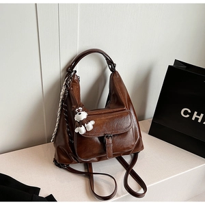 Detail of dark brown vintage faux leather backpack with silk scarf and plush dog charm