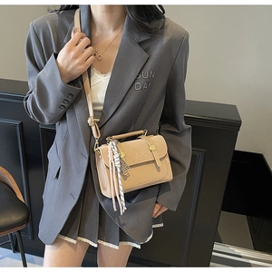 Modella che indossa una borsa a tracolla color albicocca con finiture dorate e nappa