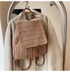 Detail of straw backpack showing woven texture and leather straps on trench coat