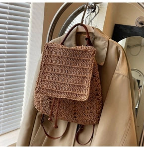Close-up of woven straw backpack featuring brown leather straps and drawstring closure