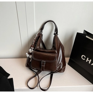 Detail of dark brown leather bag with contrast stitching and a cute animal charm
