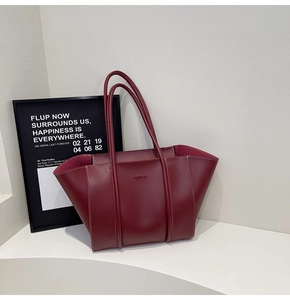 Detail of burgundy tote bag with embossed fashion text and long shoulder straps