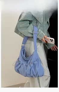 Blue nylon tote bag with drawstring details and pleated cloud design on model shoulder