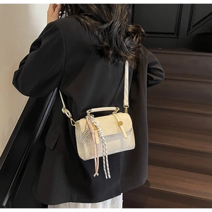 Dettaglio della borsa beige a tracolla con ciondolo a sciarpa e fermagli dorati