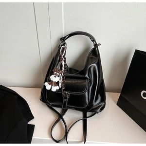 Detail of black vintage leather hobo bag with contrast stitching and puppy pendant