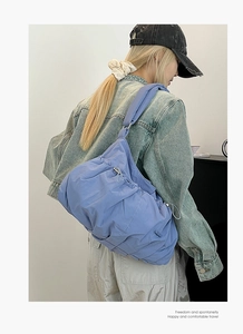 Close-up of periwinkle blue nylon tote bag featuring drawstring detail and metal buckle