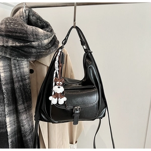 Close-up of black leather tote bag with vintage metal buckle and cute dog charm