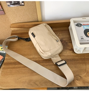 Detailed macro view of beige nylon chest bag with zipper pocket and adjustable strap