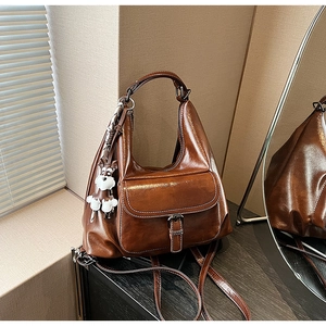 Detail of vintage brown leather tote bag with buckle pocket and white puppy charm