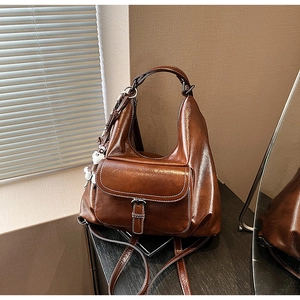 Detail of vintage brown leather backpack with contrast stitching and doll keychain
