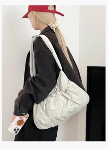 Macro detail of cream nylon shoulder bag featuring pleated texture and side drawstring