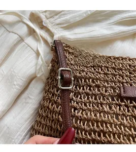 Detail of woven straw bucket bag showing adjustable leather strap and silver buckle