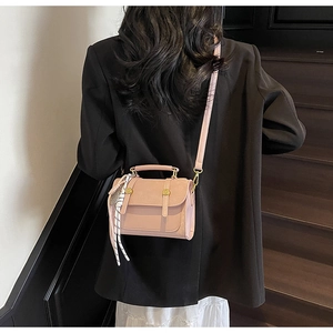 Mini borsa a tracolla rosa con foulard a pois indossata su un blazer nero elegante