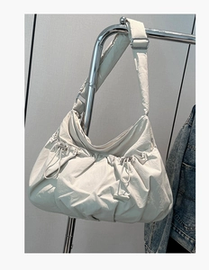 Close-up of off-white quilted nylon tote bag with drawstring texture on display rack