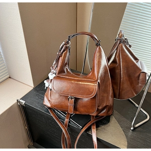 Detail of vintage brown tote backpack featuring polished finish and cute bear charm