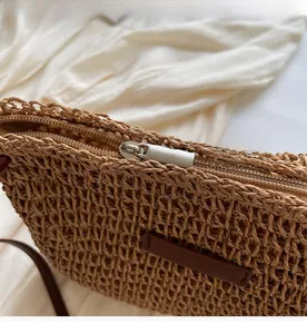 Detail of silver metal zipper closure and woven straw texture on beige bucket bag