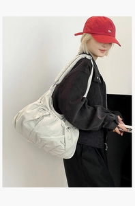 Detailed view of cream nylon tote bag with pleated texture and wide strap on model